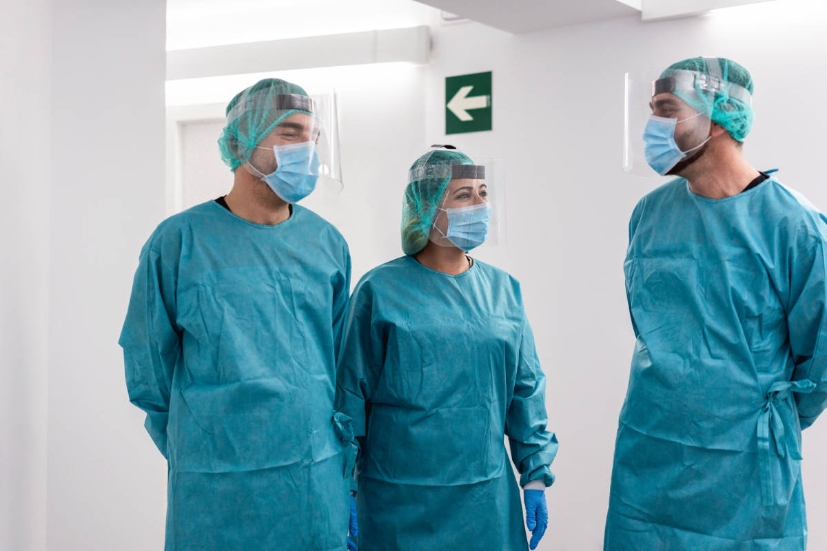 Doctors and nurse in hazmat suit talking in hospital corridor -